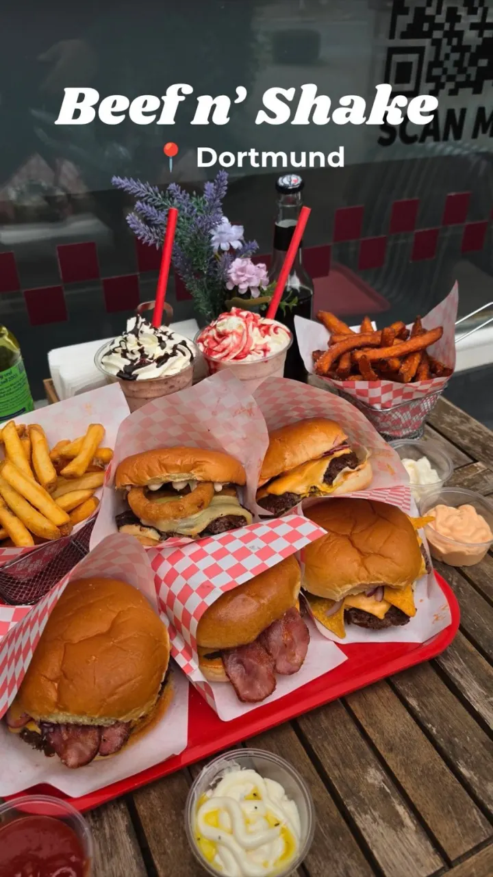 Frische Smash Burger, Sweet Potato Fries und Milchshakes auf einem roten Tablett von Beef n' Shake